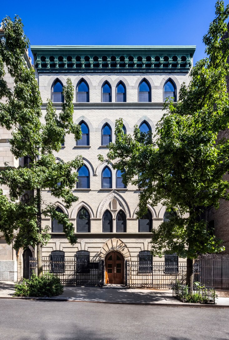 463 West 142 Harlem condos building facade with neo-Gothic arched windows on tree-lines street in Hamilton Heights.