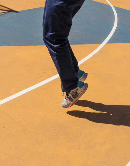 Resident in jeans and sneakers playing at basketball court at 463 w 142 condominiums in Hamilton Heights Harlem.