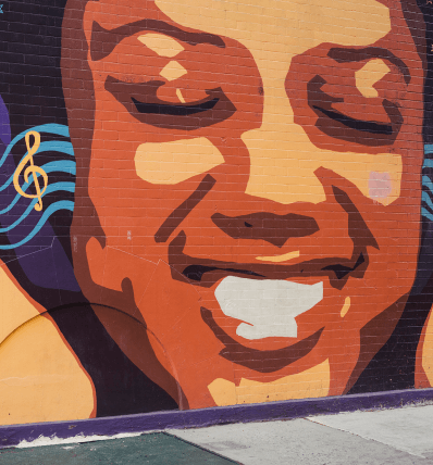 Street art mural of face with closed eyes and smile with music background near Hamilton Heights condominium at 463W142.